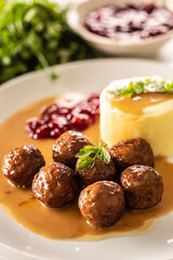 Plate serving Swedish meatballs kottbullar in sauce with mashed potatoes and cranberry sauce