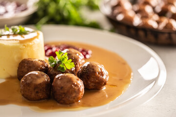 Plate serving Swedish meatballs kottbullar in sauce with mashed potatoes and cranberry sauce