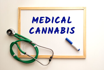 The text MEDICAL CANNABIS is written on a white office board. Nearby is a stethoscope.