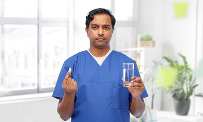 medicine, profession and healthcare concept - indian doctor or male nurse with pill and glass of water over medical office at hospital background