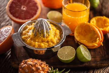 Squeezed orange pulp in a juicer with cfreshly cut citruses and a glass of juice