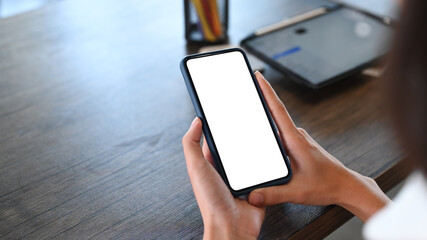 Close up view of young woman  relaxing at her workplace and using mobile phone.