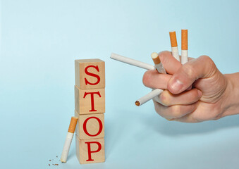 Stop smoking concept, hand holding many cigarettes and STOP text on wooden blocks. World No Tobacco...