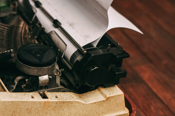 vintage typewriter with keys on a wooden background and a white sheet of paper