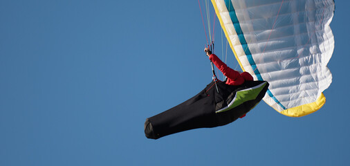 Paraglider flying his wing in a blue sky © pavel1964