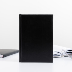 White work office desk, black book mockup with workspace accessories, pencil, notebook. Front view. Place for text, copy space, mockup