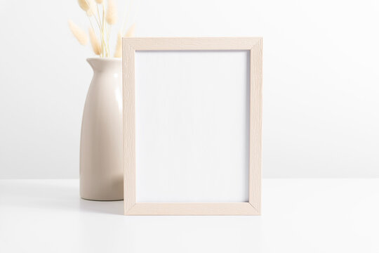 Beige Frame Mockup With Dried Flowers Lagurus In Beige Vase On White Table. Front View. Place For Text, Copy Space, Mockup