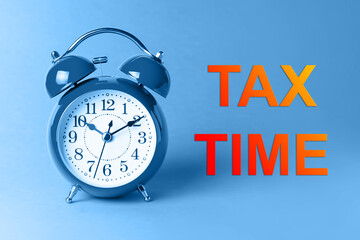 Tax time concept with clock on blue background. ..