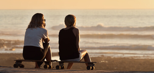 Womens sitting on a skateboard at sunset