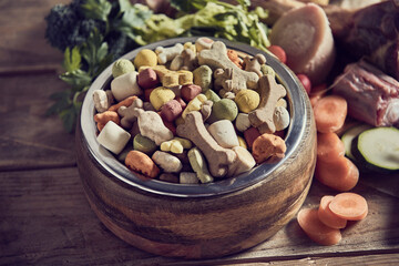 Dog food in bowl placed on table near raw vegetables