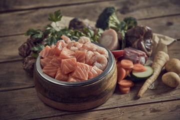Delicious raw cut seafood in bowl near assorted fresh vegetables