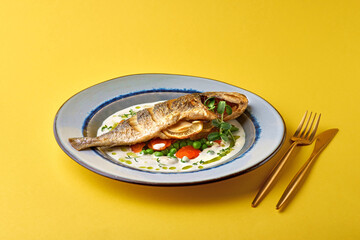 Close up of oven baked fish on on a yellow background. Healthy seafood.