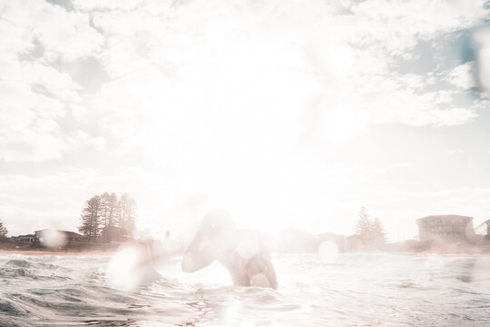 Silhouette Of Surfer Against The Sun In The Water Waiting For The Wave