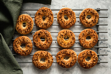 Baked round peanut cookies sprinkled with chopped peanuts on a cooling rack, marble backdrop, green linen towel. Top view horizontal photo.