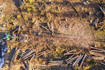 a modern harvester machine and a felled forest from above in winter