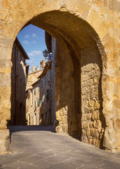 View of a medieval alley through wall gate, San Quirico d'Orcia, Italy