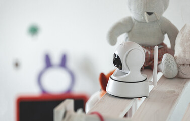 IP camera on the shelf with toys, serving as baby monitor - obrazy, fototapety, plakaty
