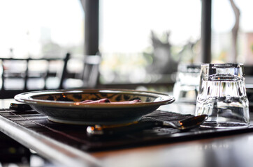 Obraz premium Table set up of old fashion plate and cutlery, glass fork and spoon with wooden plate mat in Thai restaurant