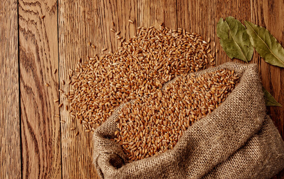 Wheat in a bag on a wooden table and dry leaves organic texture background image
