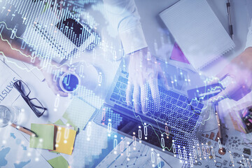 Multi exposure of man's hands typing over computer keyboard and forex graph hologram drawing. Top view. Financial markets concept.