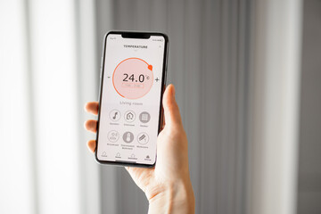 Smartphone with launched application for air temperature adjustment opposite the radiator. Health microclimate at home concept. 