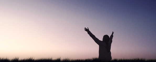 Silhouette of a girl raising arms to sky evening