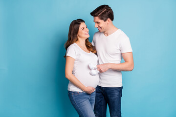 Profile portrait of two persons look each other eyes baby booties on fingers stomach isolated on blue color background