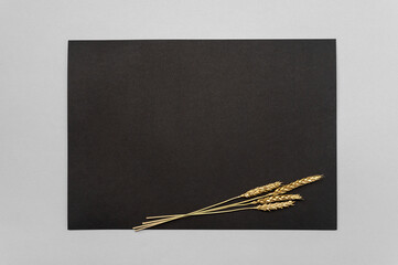 Black invitation card mockup with a golden dried eucalyptus decoration on a neutral table. Black...