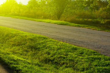 Sunset in the countryside. Yellow light on the green lawn and road.