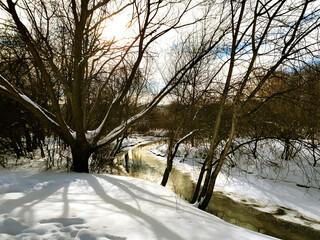 Mobile photo. An unsized creek in the middle of snow-covered shores.