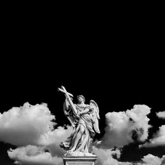 Angel holding the Holy Cross with heavenly sky, A 17th century baroque masterpiece at the top of Sant'Angelo Bridge in the center of Rome (Black and White with copy space above)