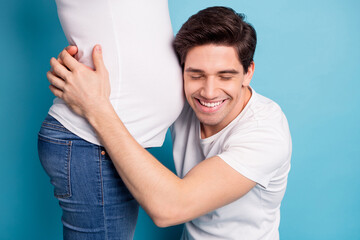 Cropped photo of impressed man hug listen baby in stomach closed eyes wear white t-shirts isolated on teal color background