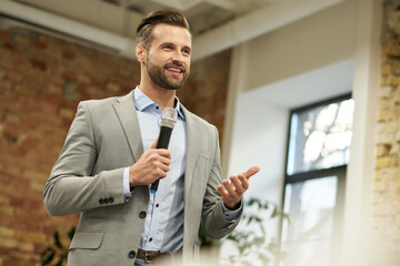 Confident man speaking in the microphone and smiling