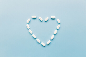 heart-shaped medicine pills on a blue background