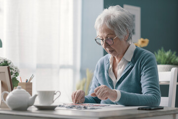 Senior woman sitting at desk and solving a puzzle