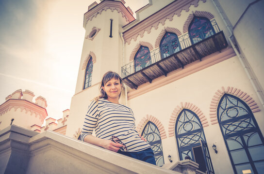 Young beautiful girl traveler posing near palace castle building in Kosava Kossovo in sunny summer day, blue sky background, vacation in Brest region, Belarus