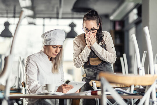 Shock And Surprise On Faces Of Female Gastro Employees Sitting Over Numbers After Hours In The Bar