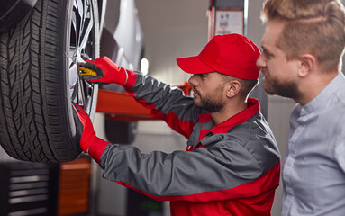 Mechanic with customer checking car wheel © kegfire