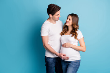 Photo of cheerful sweet pretty adorable couple expecting child arm hand belly looking each other isolated blue color background