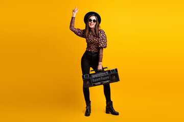 Full length body size photo of funky brunette keeping cassette recorder listening song singing isolated vivid yellow color background