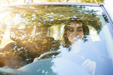 Cheerful pretty girl drives the car with smile on her face. Photo of windshield of automobile with...