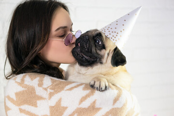 Celebrating Birthday of  pug  Dog  .  Young  woman kissing and hugs  pug dog .