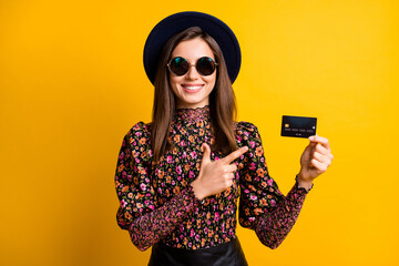 Photo portrait of stylish girl in headwear pointing finger credit card smiling in sunglass isolated...