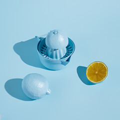 Monochrome layout with blue colored lemon and squeezer on pastel background. Minimal citrus fruit concept. Making of fresh summer juice.