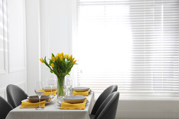 Beautiful Easter table setting with yellow tulips indoors