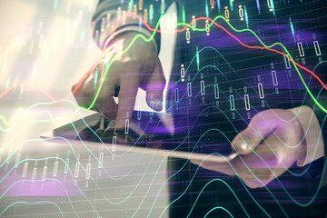 Double exposure of man's hands holding and using a digital device and forex graph drawing. Financial market concept.