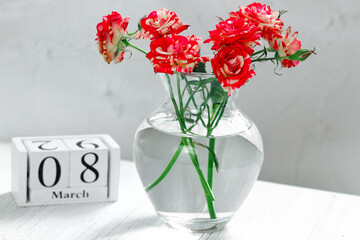 On a wooden calendar the inscription March 8 with a bouquet of roses.