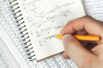 Math formulas are written in pencil in a notebook holding man in hands, math problems
