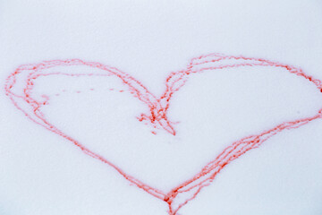 A big heart painted in red on the snow close up.