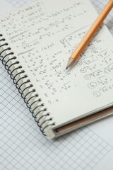 Math formulas are written in pencil on a piece of paper, math problems